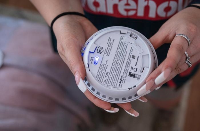 A woman holding a smoke alarm.