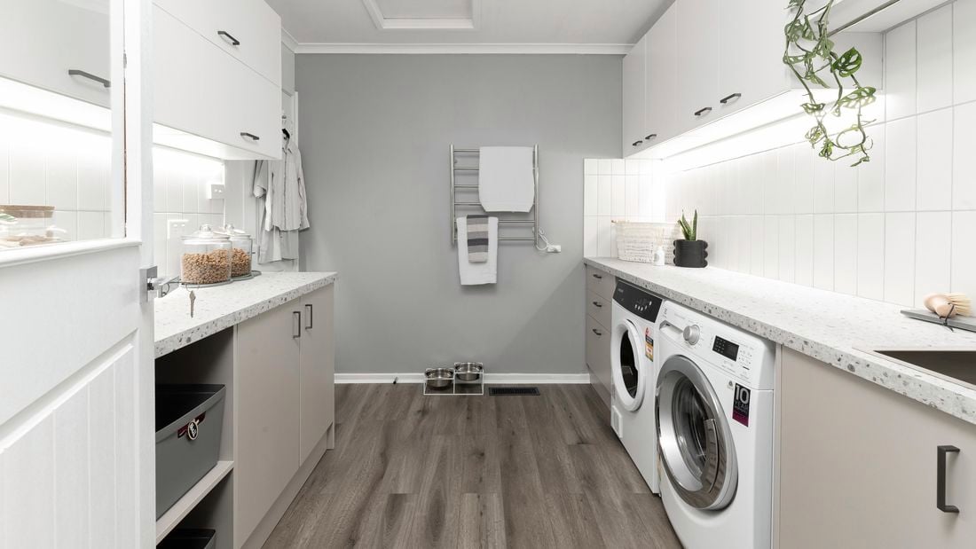 Laundry with cabinets, washer, dryer and timber flooring.
