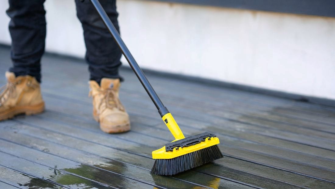 Person with a broom painting a deck