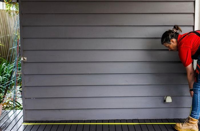 A person measures the dimensions in a patio.
