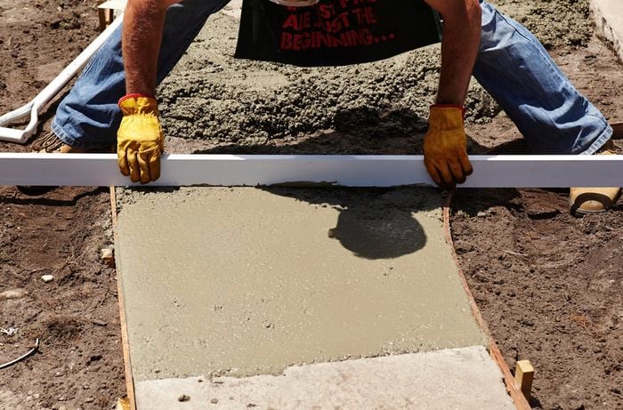 Bunnings team member using a straight edge to level the wet concrete surface