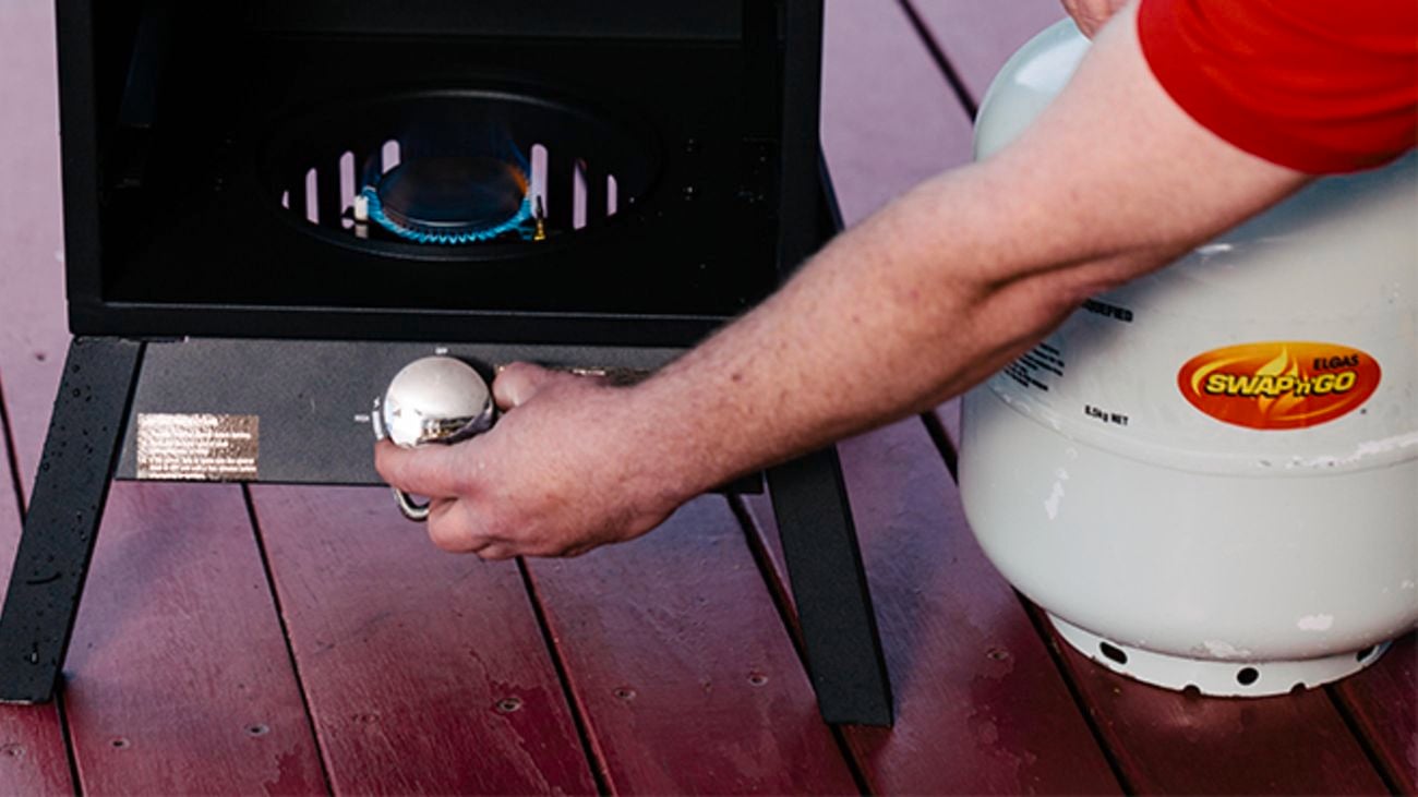 Person adjusting dial on BBQ.