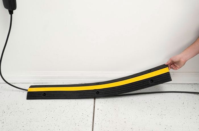 A person is placing a protective cable cover over an EV charging cable to make it safer and easier to manage.  