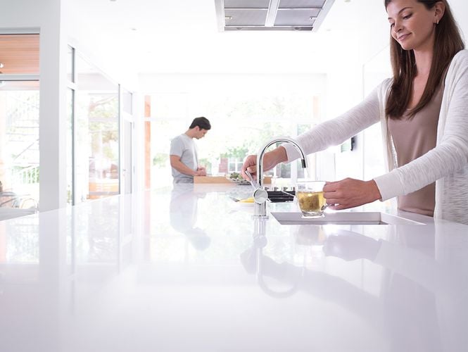 Woman filling glass with water from kitchen tap