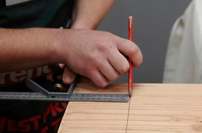 A square rule and pencil being used to mark a position for legs
