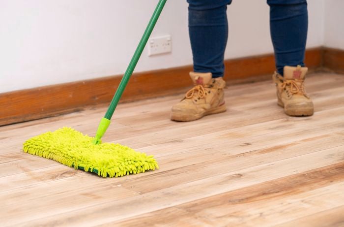 A person is using microfibre mop to remove fine dust and prepare the surface for sealing.​​ ] 