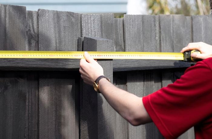 Bunnings team member measuring the topmost part of a fence