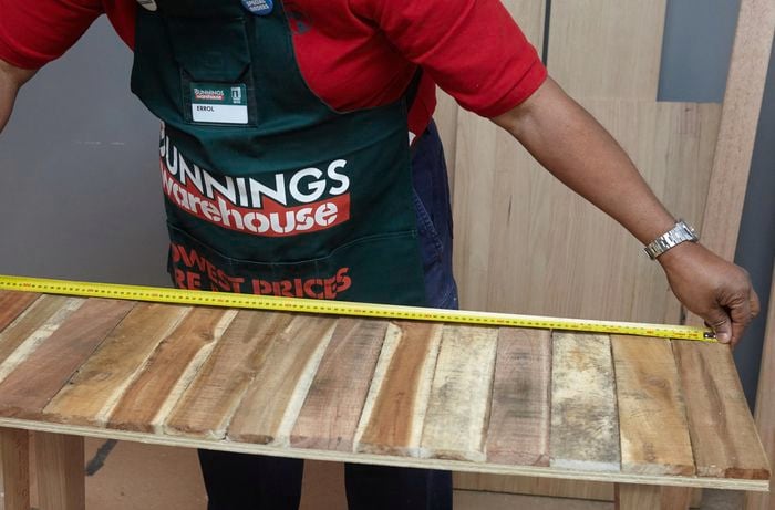 Person measuring the length of a table with a tape measure