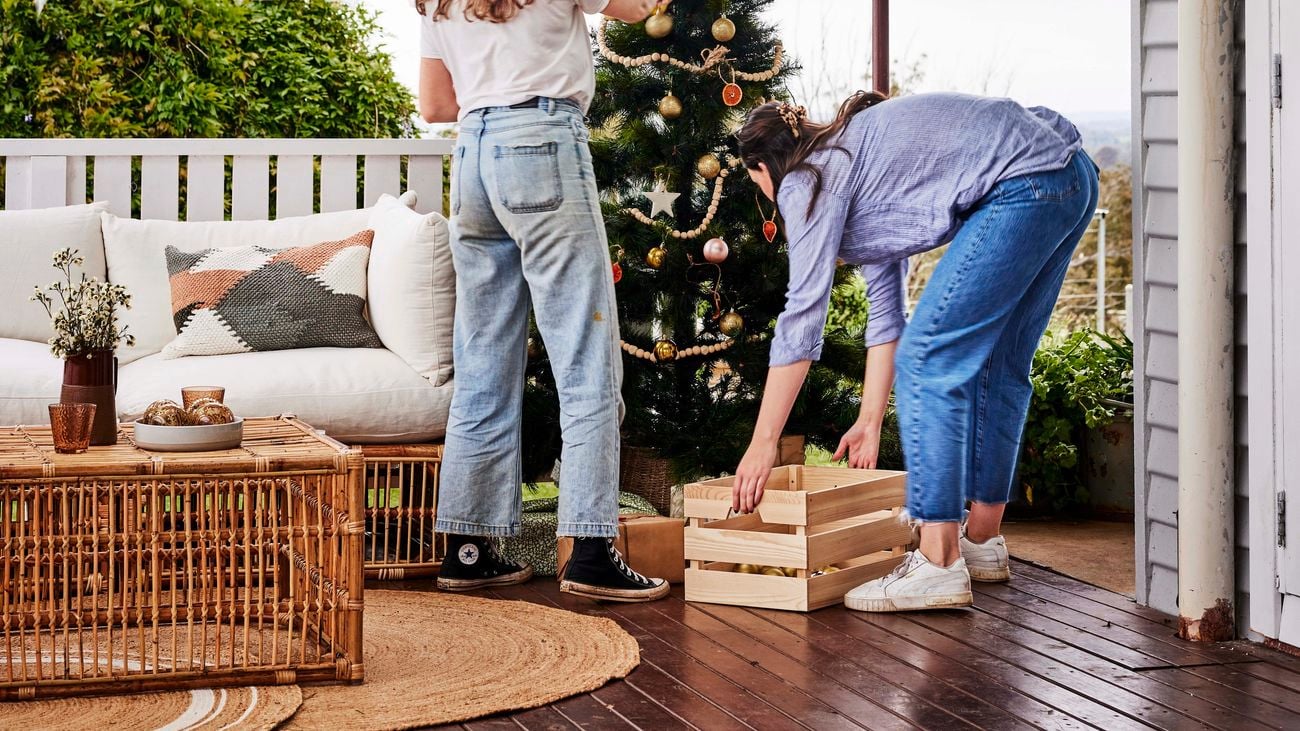 Two women take down Christmas decorations from a Christmas tree