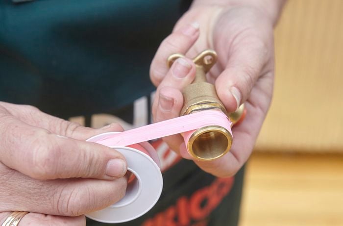 Person taping part of garden hose attachment.