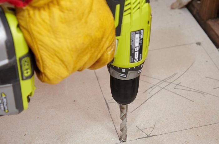 A hole being drilled into the floor sheet to make room for a shower sump