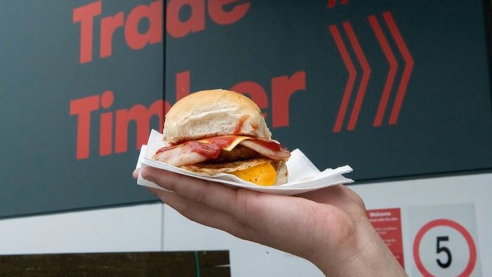 A person holding up a bacon and egg roll.