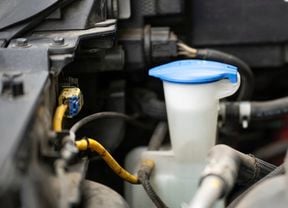 A car’s windshield washer fluid reservoir is shown with its blue cap closed.