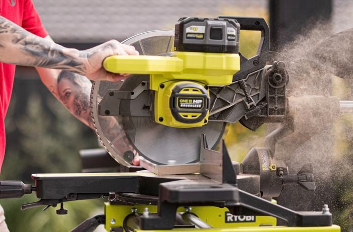 A Bunnings Team Member is creating a cut in skirting board using Ryobi mitre saw.  ] 