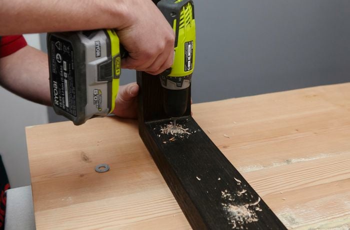 Holes being drilled into the legs and base of a wooden table for later screwing into place