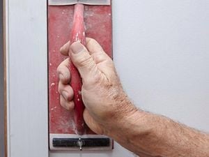 Person sanding a wall.