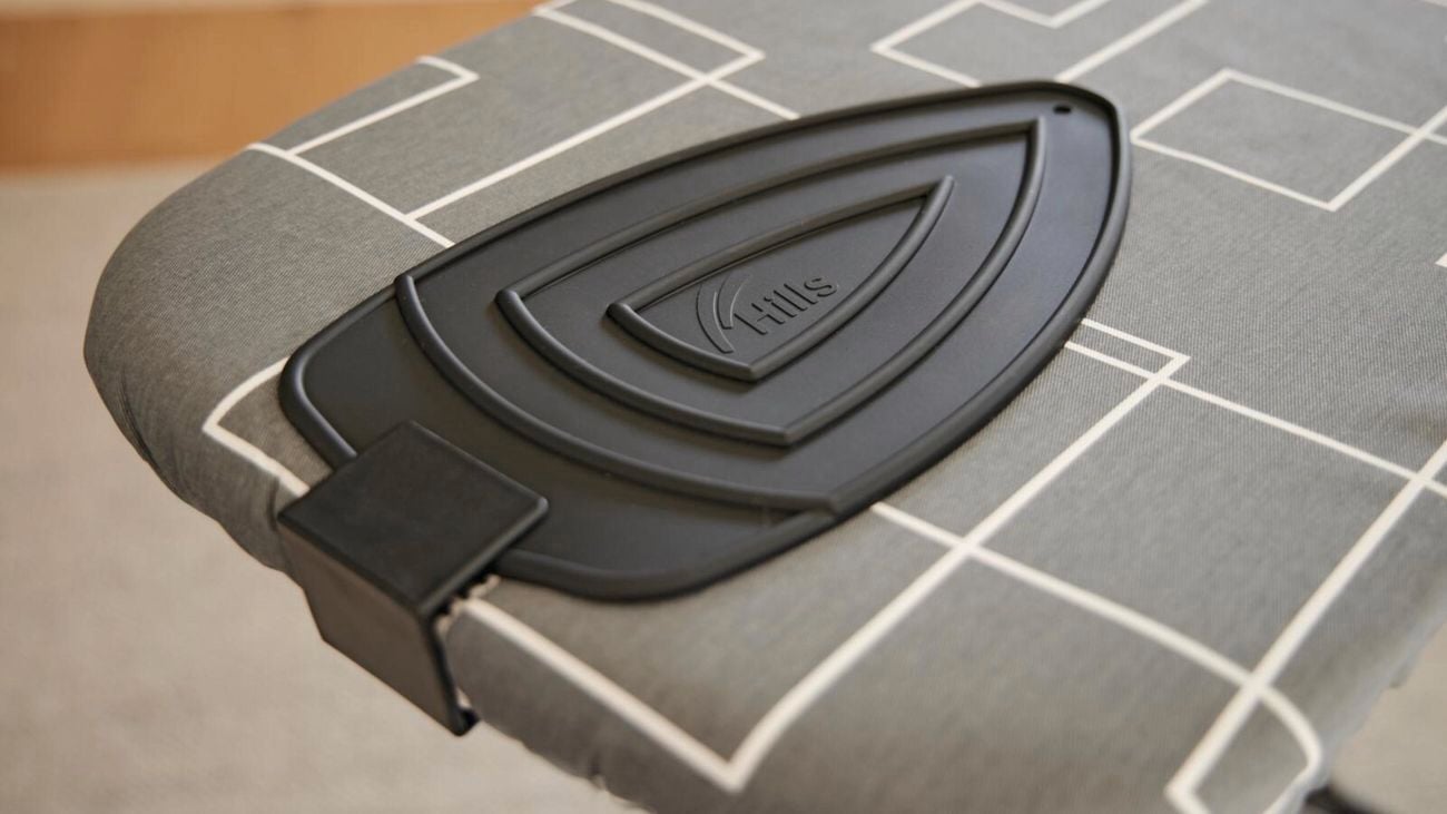 A closeup of an ironing board with a silicone iron holder