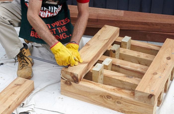 Framework for an outdoor day bed being measured for bolts with a square rule