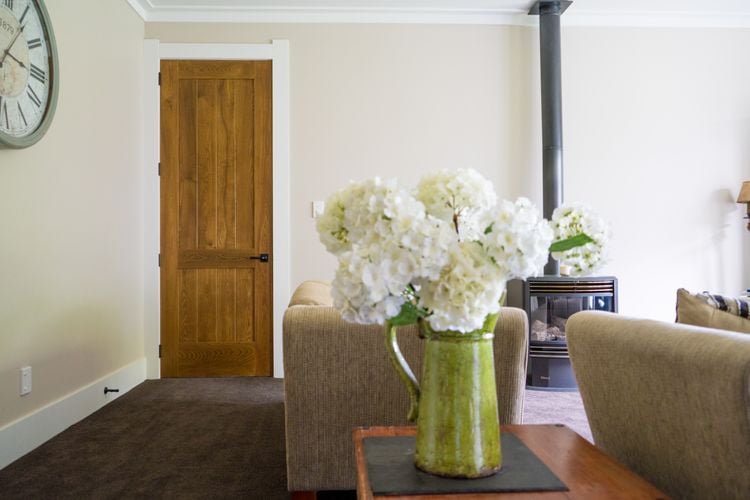 Lounge room with two beige couches, a fireplace and a wooden door
