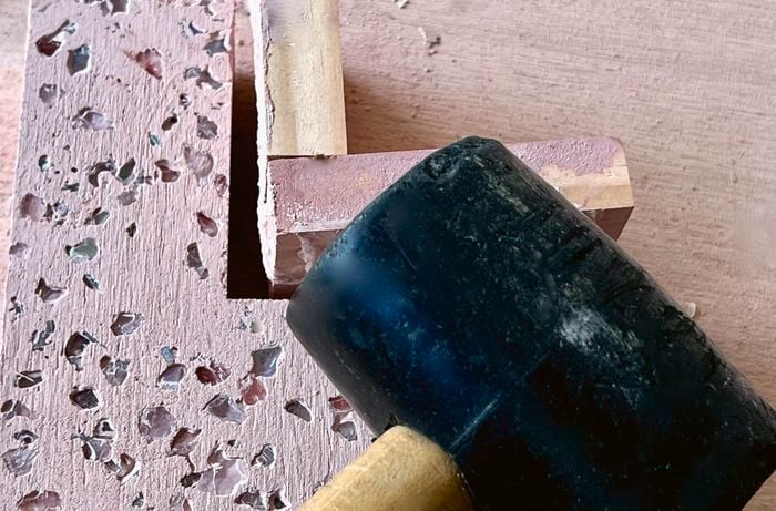 A person uses a mallet to remove the mould from a cured pink terrazzo bookend.