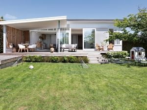 Backyard with decking, outdoor furniture and large lawn.