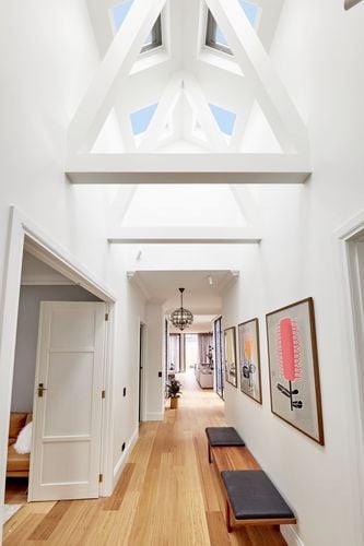 Long hallway painted white with timber floors, exposed roof trusses and four skylights