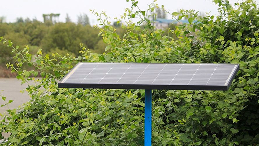 KT solar panel mounted on a pole in an outdoor setting surrounded by greenery.