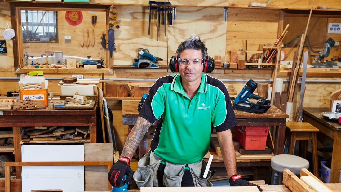 A builder in his workshop posing with a Makita sander wearing a hi-vis green shirt