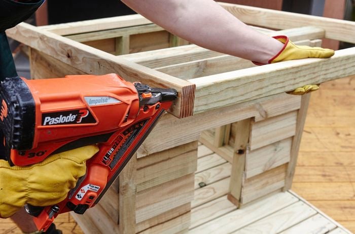 Person drilling timber frames of DIY dog kennel together.