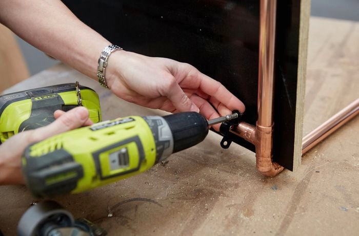 Person attaching brackets to copper frame