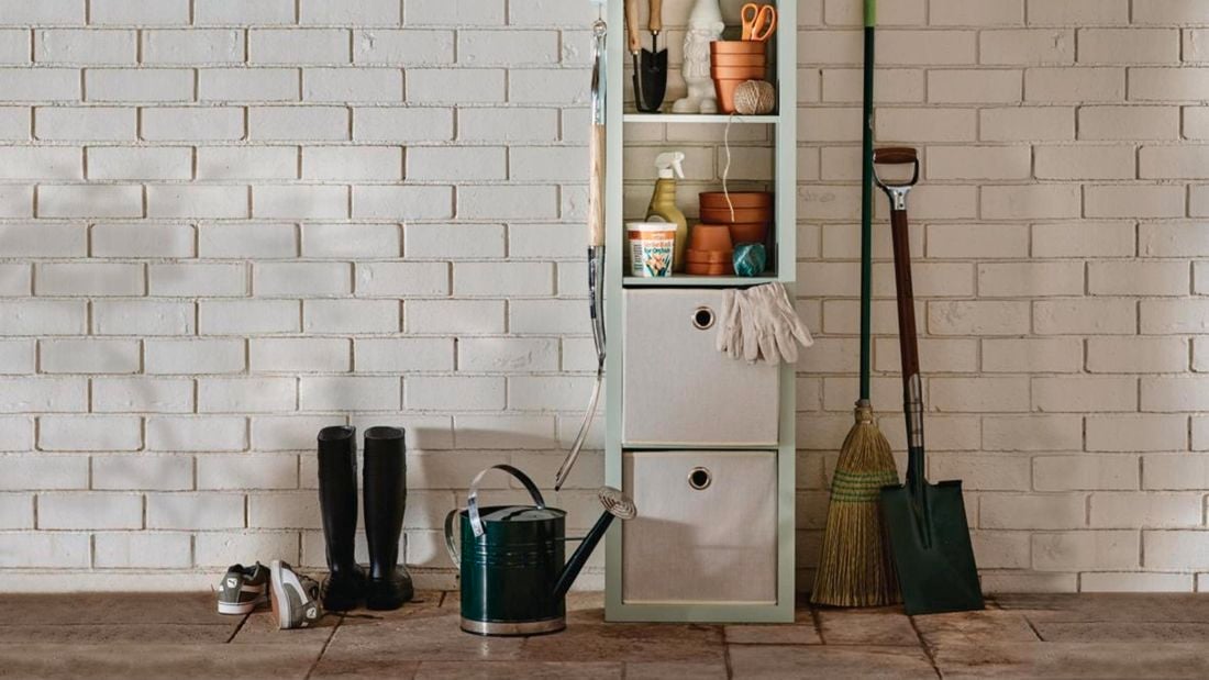 Vertical storage cube with gumboots, watering can, garden gloves and shovel.