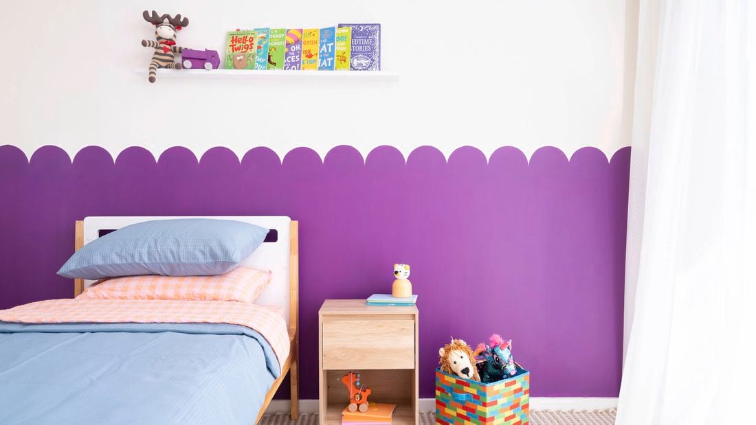 A playful purple scalloped wall feature creates a fun backdrop in a kids bedroom. 