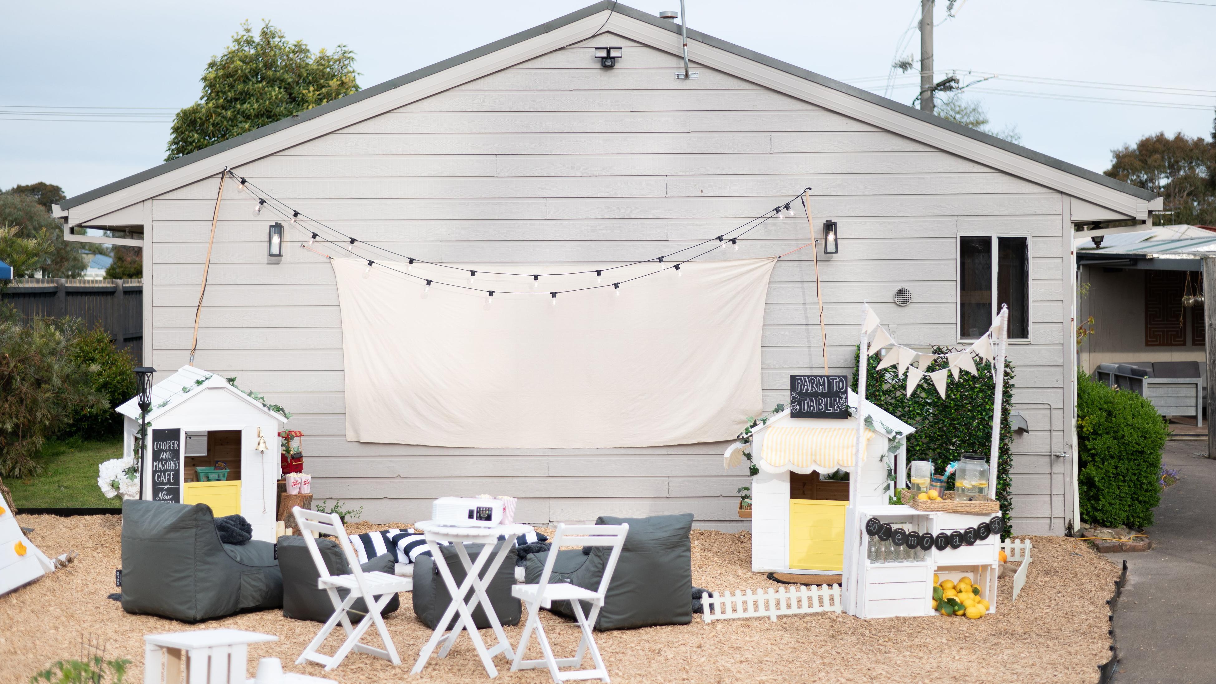 Outdoor furniture in front of a wall with canvas screen and fairy lights