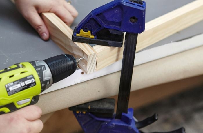 Person drilling two bits of timber together to create bookshelf side.