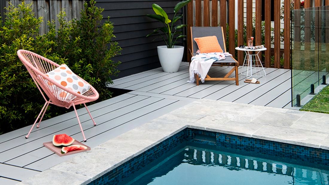 Pool with pale coloured decking and outdoor furniture