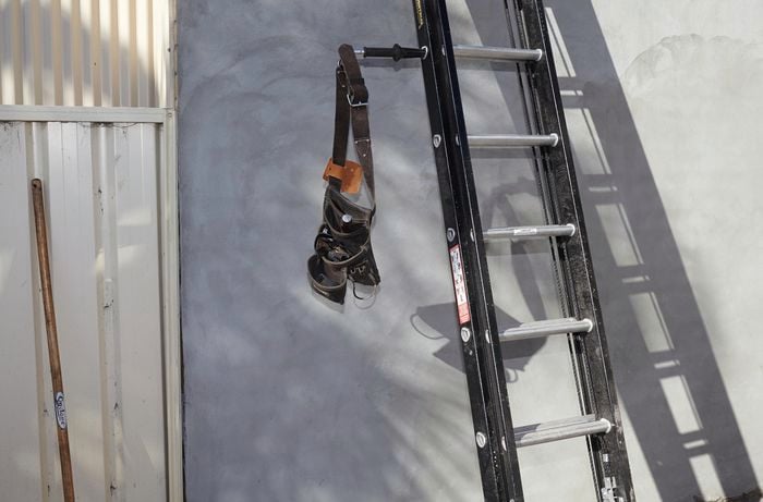 A tool belt hanging off a ladder limb on an extension ladder
