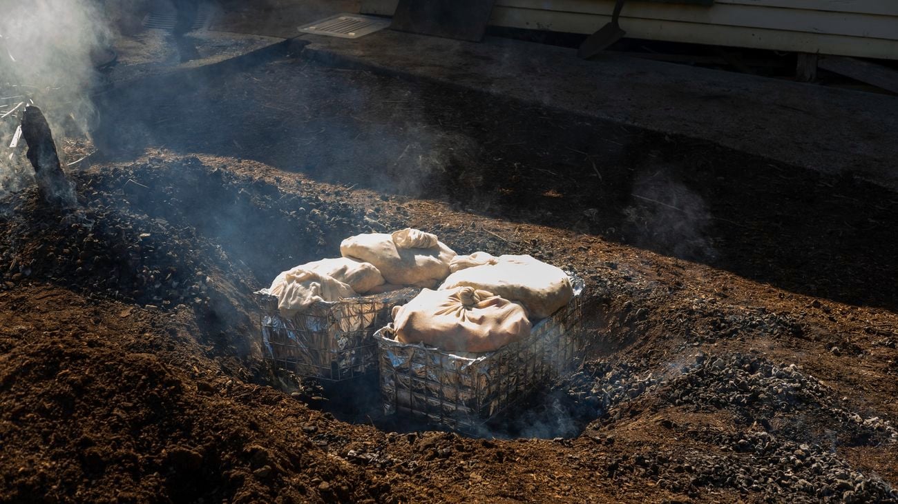 A hole in the ground, with baskets full of hessian sacks inside them.