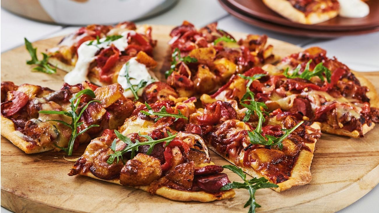Chorizo and potato pizza on a round timber board