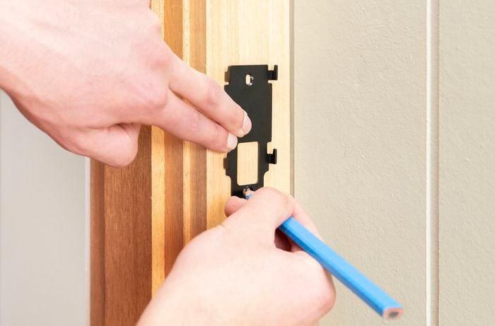 A Bunnings Team Member is marking the drill points while holding the mounting brackets in the desired position.