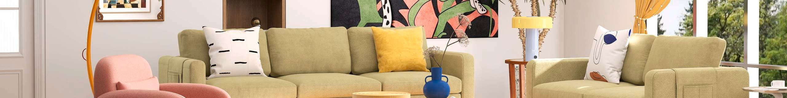 A furnished modern lounge room with two green couches with cushions on them, a pink chair, paintings on the wall and a small table in it.