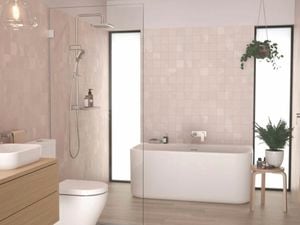 A modern Caroma bathroom in neutral tones featuring a freestanding bathtub flanked by floor-to-ceiling windows, a frameless shower screen and a timber vanity