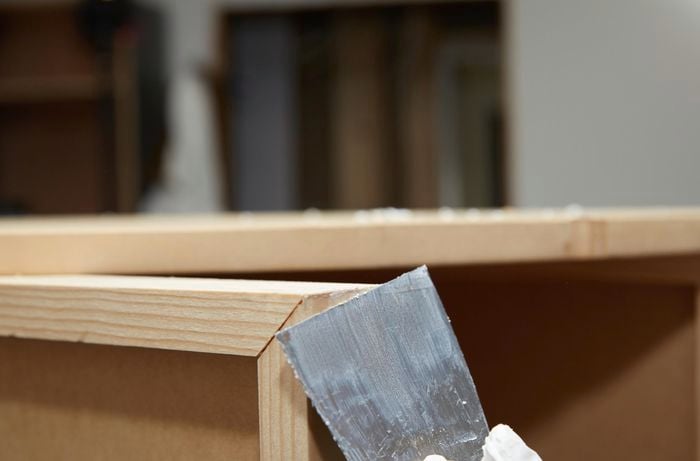 Person filling gaps in timber with putty\