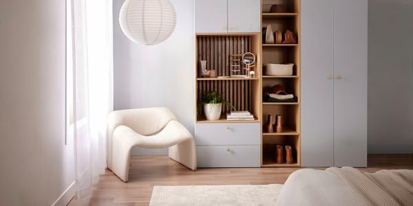 White storage cabinet in a bedroom with a white chair and a bed in it.