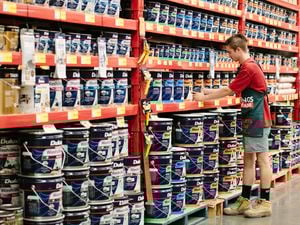 Bunnings team member re-filling a shelf with paint