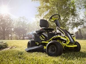 Ryobi ride-on lawn mower parked in a backyard