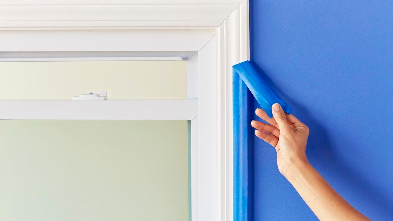 Person removing Scotch painter’s tape from a door frame