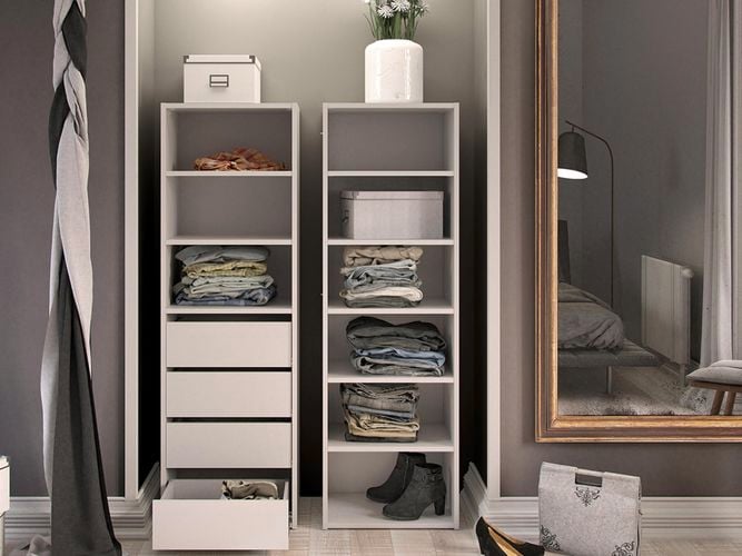 Two shelving units next to a wall in a bedroom with a mirror on the wall