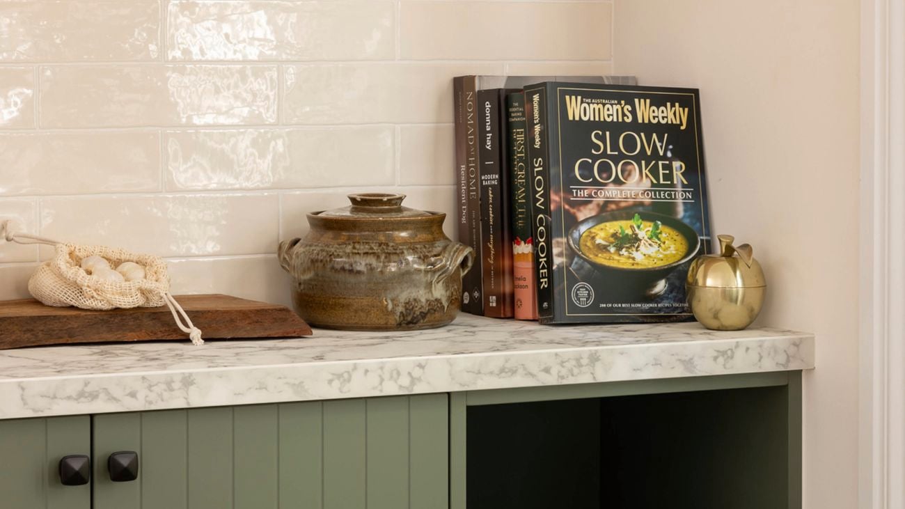 Green kitchen with books and chopping board in focus