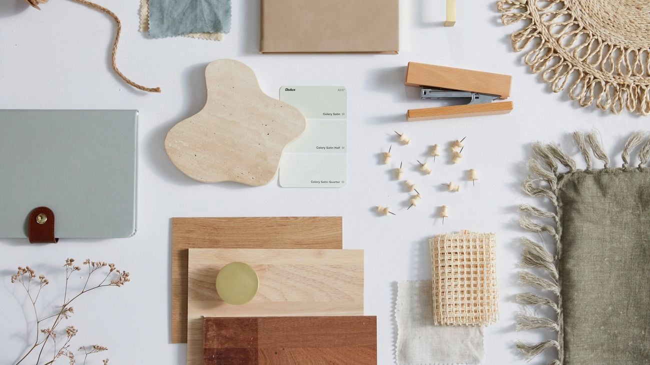 A flatlay of a moodboard featuring interior accessories and materials in pale green and neutral colours.