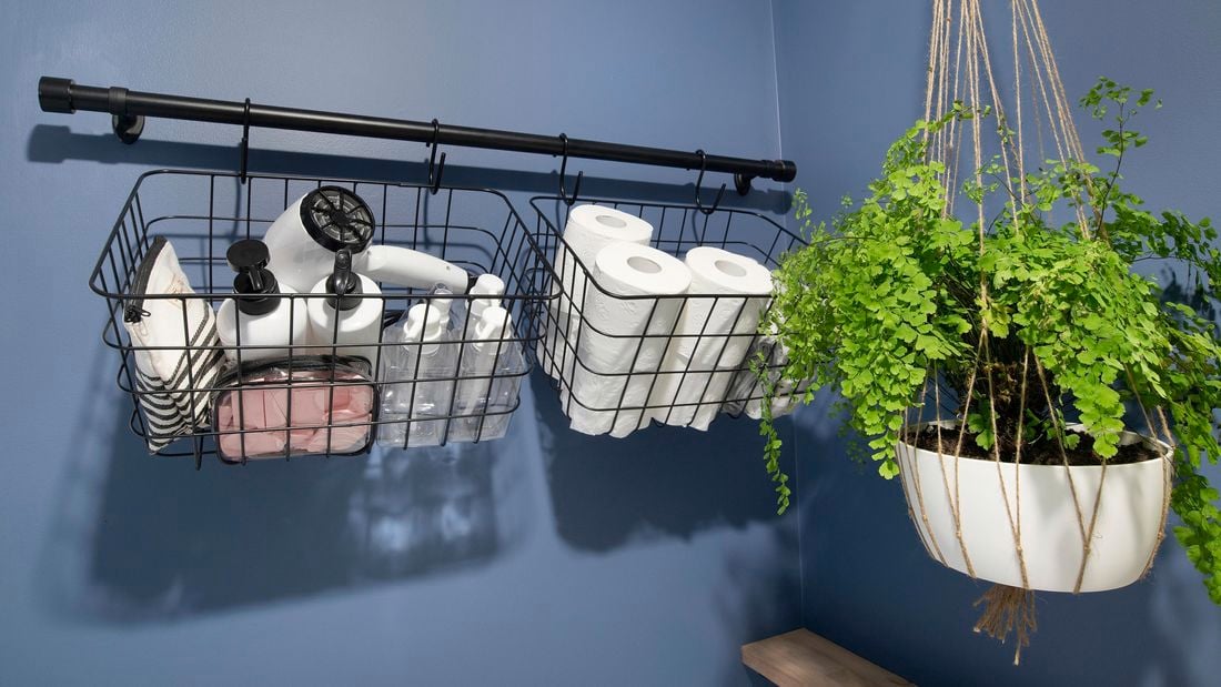A wall mounted rail holding storage baskets in a bathroom